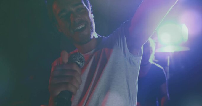 Stage cue flash, lead singer raising mic and singing, leaning and gesturing to engage crowd