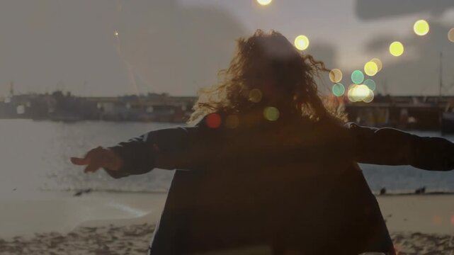Woman spinning on shore, wind causing spin, arms open, filming ad with animated flare echoing spin
