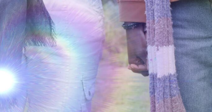 Vertical video: Couple walking, hands shifting then clasping, lens flare framing watch for romance