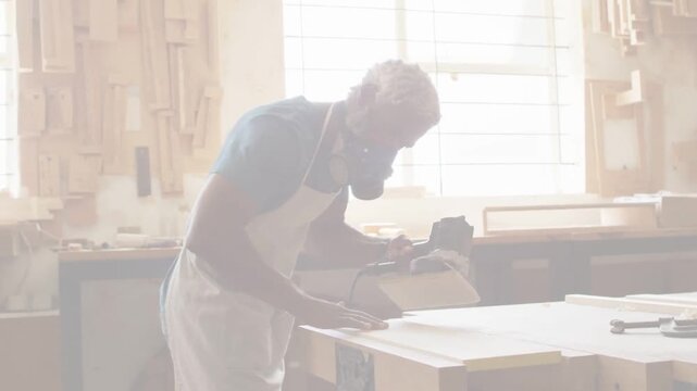 Vertical video: Placing sander, woodworker in apron and mask sanding panel on bench for smoothing