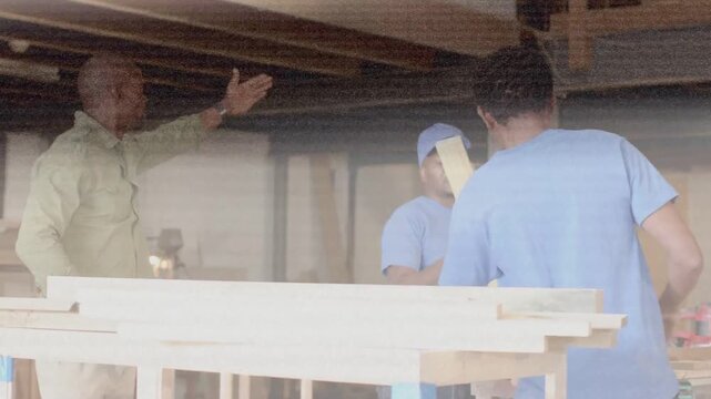 Vertical video: Raising left hand lead green shirt leading two blue shirts aligning lumber on site