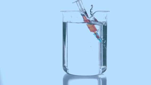 Animation of red dots over syringe with reagent in glass on blue background