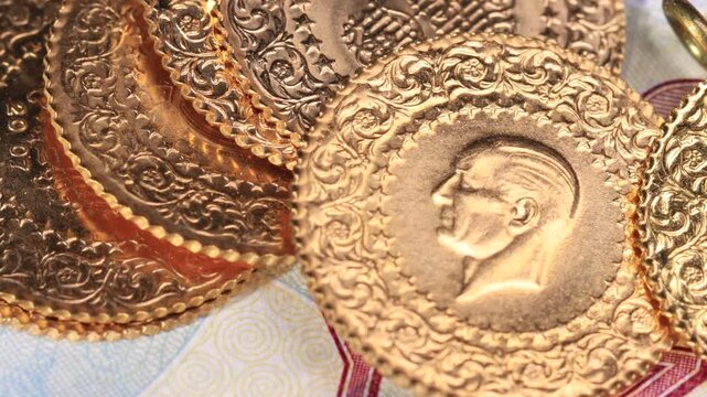 Close-up of Turkish Republic gold coins with Ataturk portrait ornate engraved borders and chained pendant coin slowly panning right on banknote background