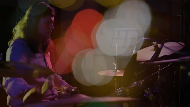 Male drummer raising arm hitting cymbals and snare in music rehearsal bokeh showing kit for record