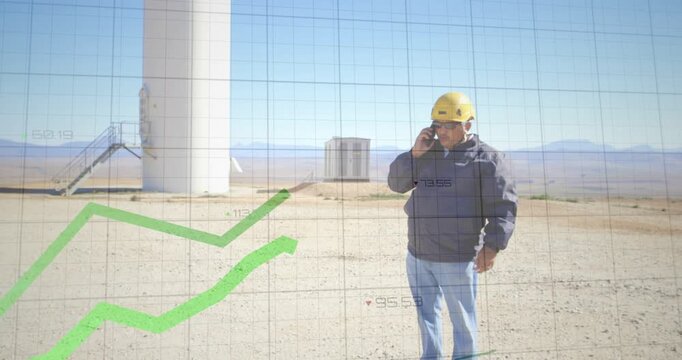 Vertical video: Answering tech with yellow helmet holding phone viewing turbine data, copy space