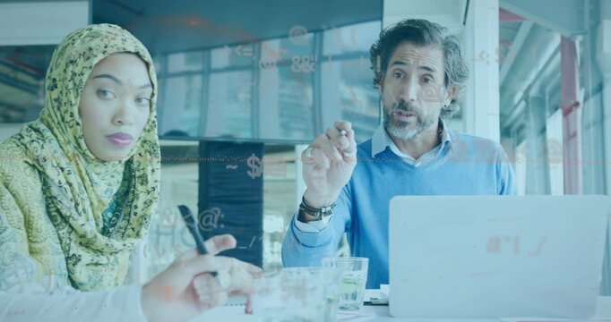 Man starting to speak, gesturing and using laptop to explain plan; woman observing, writing notes