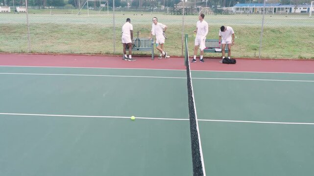 Four tennis players ending session, collecting gear at baseline while overlay hovering over court