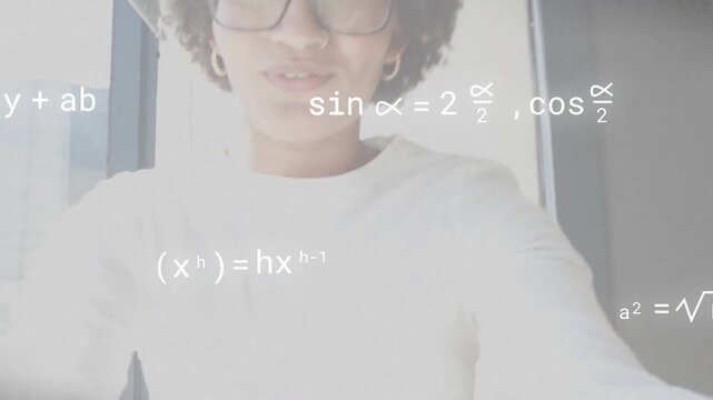 Vertical video: Smiling at cam, woman in glasses turning right at window teaching math with overlay