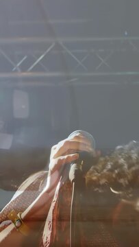 Vertical video: Singer raising mic and singing at music set, hitting high notes amid stage lights
