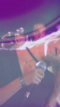 Vertical video: Lead singer hearing band cue, singing into mic for music gig while lights streaking