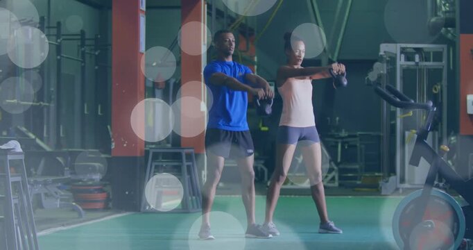 Workout partners starting hip hinge, kettlebell swinging in gym for strength, bokeh overlay