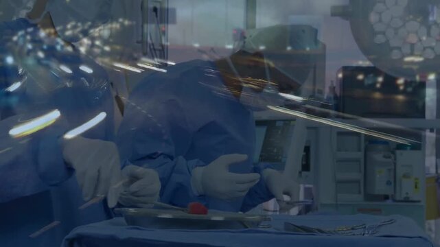 Surgeon initiating surgery by lifting red tool, assistant passing clamps, monitor displaying vitals