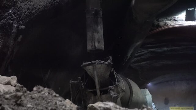 Moment of pouring concrete from above into a mixer inside the tunnel via a shaft from the surface. Challenging working conditions in mining and underground projects.