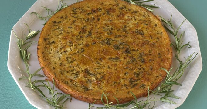 Traditional Italian socca (chickpea pancake) with rosemary herb. Table spin.