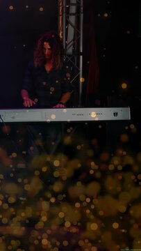 Vertical video: Male keyboardist placing hands on keys, performing music with golden bokeh overlay