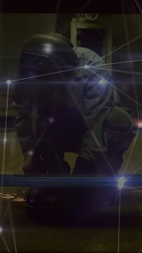 Vertical video: Welder kneeling bringing tool to rail, grinding sparks, cutting, flares on helmet