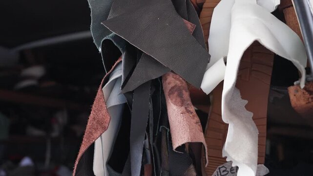 Close-up of assorted leather and synthetic scraps at a street cobbler workspace in Malaysia, showing material textures, reuse, and the raw elements of traditional shoe repair.