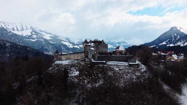 Establishing drone shot of Gruyeres Castle with snow in winter during the day in Canton of Fribourg, Switzerland