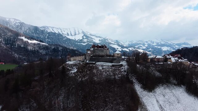 Aerial: famous Gruyeres Castle with snow in winter during the day in Canton of Fribourg, Switzerland, parallax drone shot