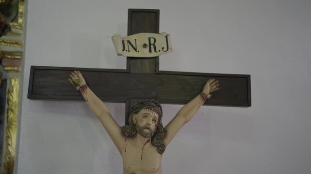 Close up of a wooden crucifix statue of Jesus Christ with crown of thorns and INRI sign.