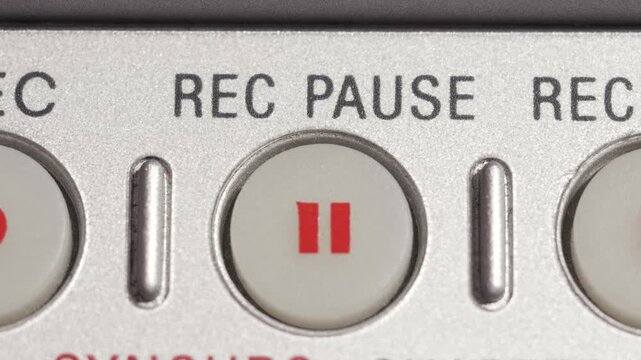 Close up of REC PAUSE button pressed with red pause icon on silver panel