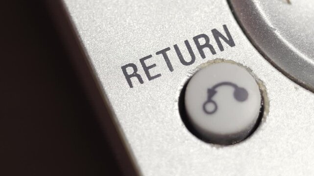 Macro close up of return key pressed on silver device panel for back navigation