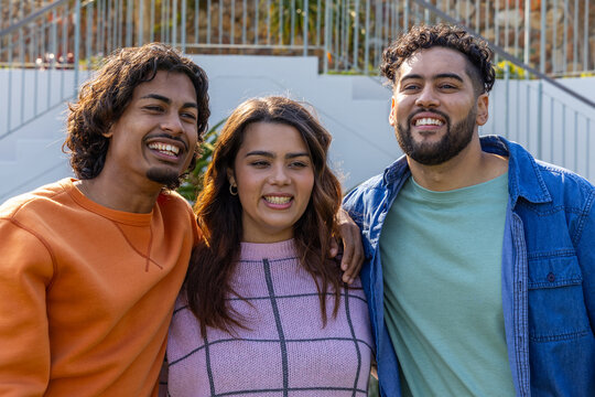 Three friends posing and smiling on exterior steps by metal railing with colorful clothing