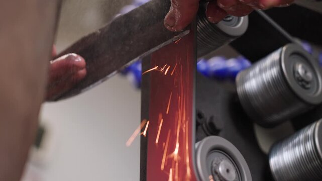 Slow motion close-up of knife sharpening on a grinding wheel in Malaysia, with bright sparks flying, highlighting precision, craftsmanship, and metalworking process. UHD.