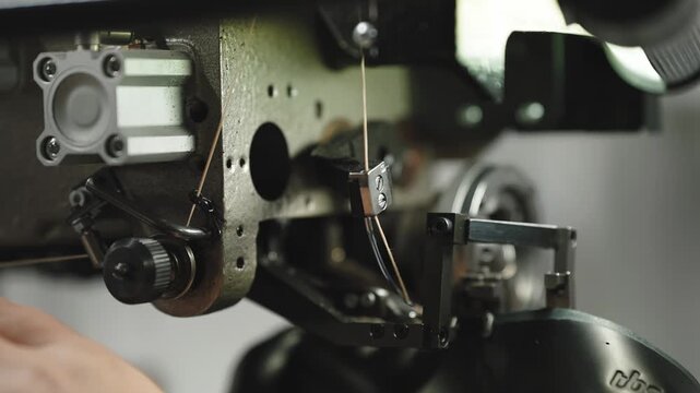 Technician adjusts thread guide on heavy industrial textile machine mechanism