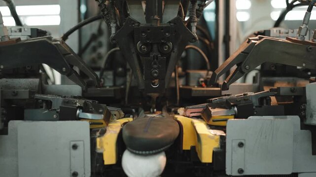 Automated lasting machine clamps and shapes shoe upper onto last in footwear factory