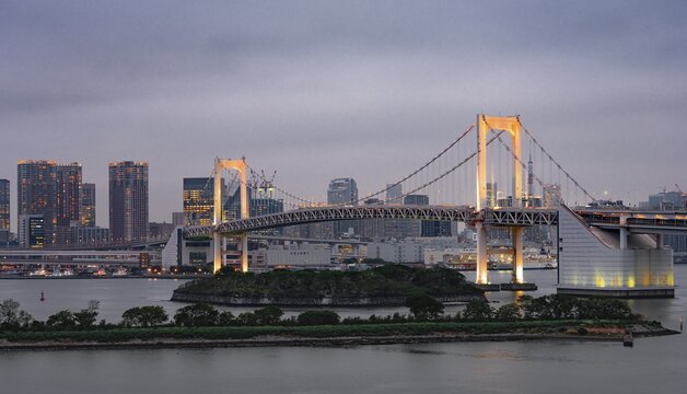 View of skyline with skyscrapers and illuminated Rainbow Bridge in the evening, Odaiba, Tokyo, Japan