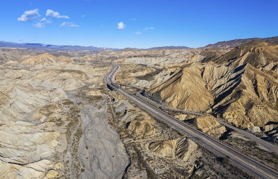Bare ridges of eroded sandstone in the Tabernas Desert, transected by the A92 highway, aerial view, drone shot, Almeria province, Andalusia, Spain