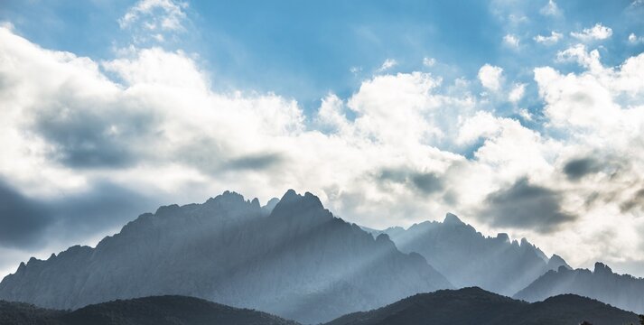Sun through clouds against mountains, silhouette of the mountains with Monte Cinto, Col de Vergio, Cinto Massif, Corsica, France