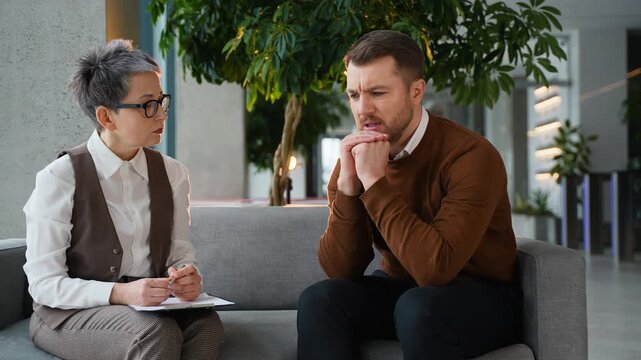 Depressed man talking with a female psychologist during therapy session