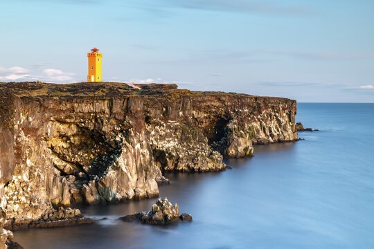 Orange lighthouse of &Ouml;ndverdarnes stands at cliff coast, rocky coast of lava rock, long time exposure, &Ouml;ndver&eth;arnes, Sn&aelig;fellsj&ouml;kull National Park, Snaefellsnes Peninsula, Sn&aelig;fellsnes, Vesturland, Iceland