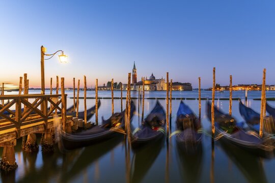 Venetian gondolas at St. Mark's Square in the evening light, blue hour, in the back monastery San Giorgio Maggiore, district San Marco, Venice, region Veneto, Italy