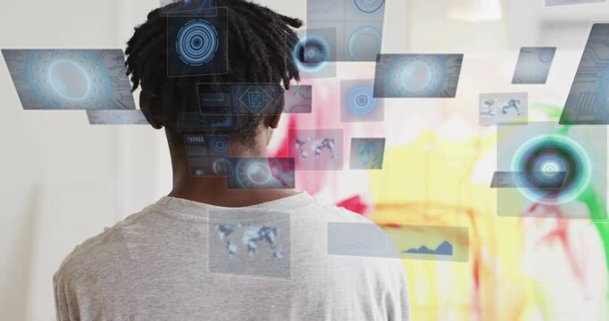 Man standing facing canvas in art studio on cue panels emerging overlapping upper back showing data