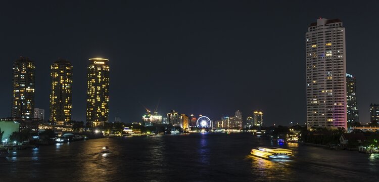 Skyline with Ferris wheel and boat on the river Mae Nam Chao Phraya, at night, Bangkok, Thailand