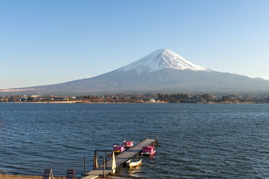 Footbridge with pedal boats, view over Lake Kawaguchi, back volcano Mt. Fuji, Yamanashi Prefecture, Japan