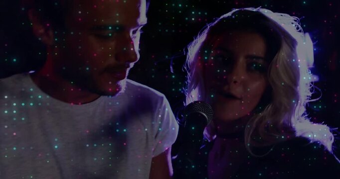 Musical duo singing duet, female raising mic, male harmonizing under purple light, dots overlaying