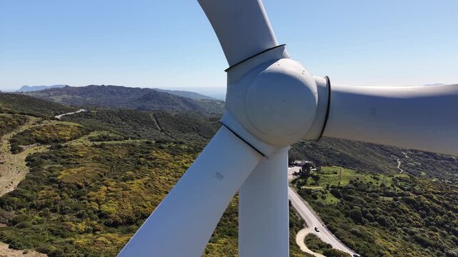 Close up on wind turbine turbine with green mountains and the strait of Gibraltar in the background