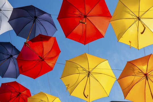 Many colorful umbrellas, parasols, hanging in the air, sunshine in front of blue sky, Imst, Tyrol, Austria