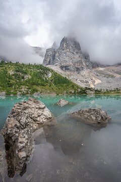Turquoise green mountain lake, Sorapis lake, Lago di Sorapis with reflection, cloudy mountain peak Dito di Dio, Dolomites, Belluno, Italy