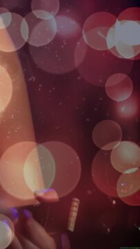 Vertical video: Hand entering sparking cam pull as singer leaning, singing at mic amid music bokeh