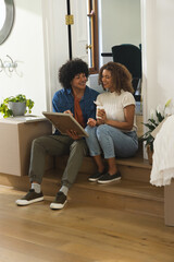 African American couple sitting on wooden step inside home holding framed picture and coffee cup © wavebreak3