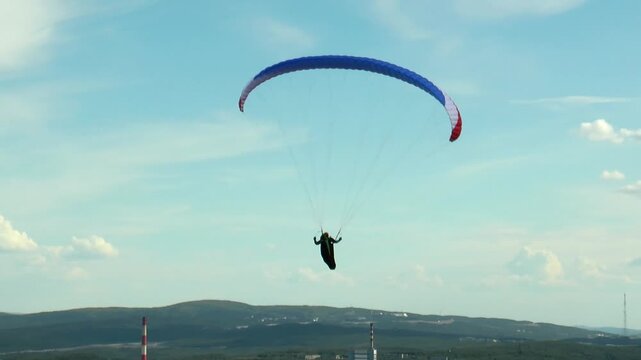 Paraglider gently floats in the sky against a background of beautiful clouds summer day.