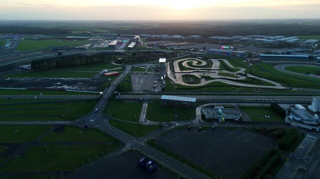 High angle drone perspective of a massive Motorsports complex in Silverstone England at dusk with winter light and track infrastructure.