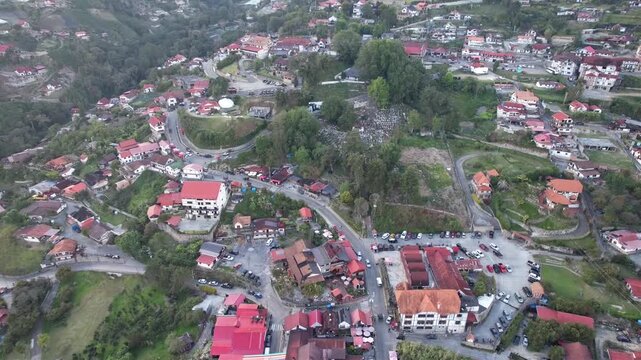 aerial view moving backwards to reveal the iconic German-style red roofs and central church of a picturesque mountain settlement.