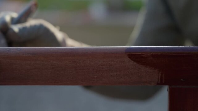 Macro shot of glossy varnished wooden chair frame rail with wet lacquer sheen outdoors