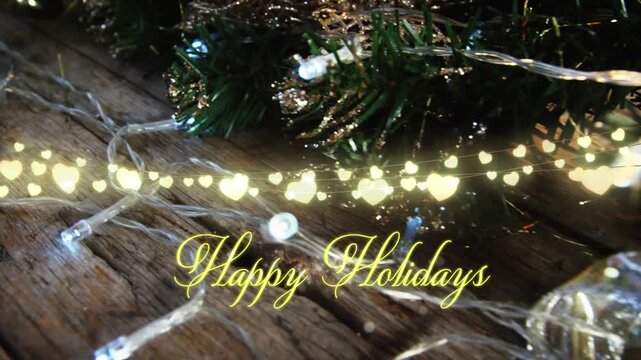 Animation of text, happy holidays, in yellow, over string lights and decorated christmas tree